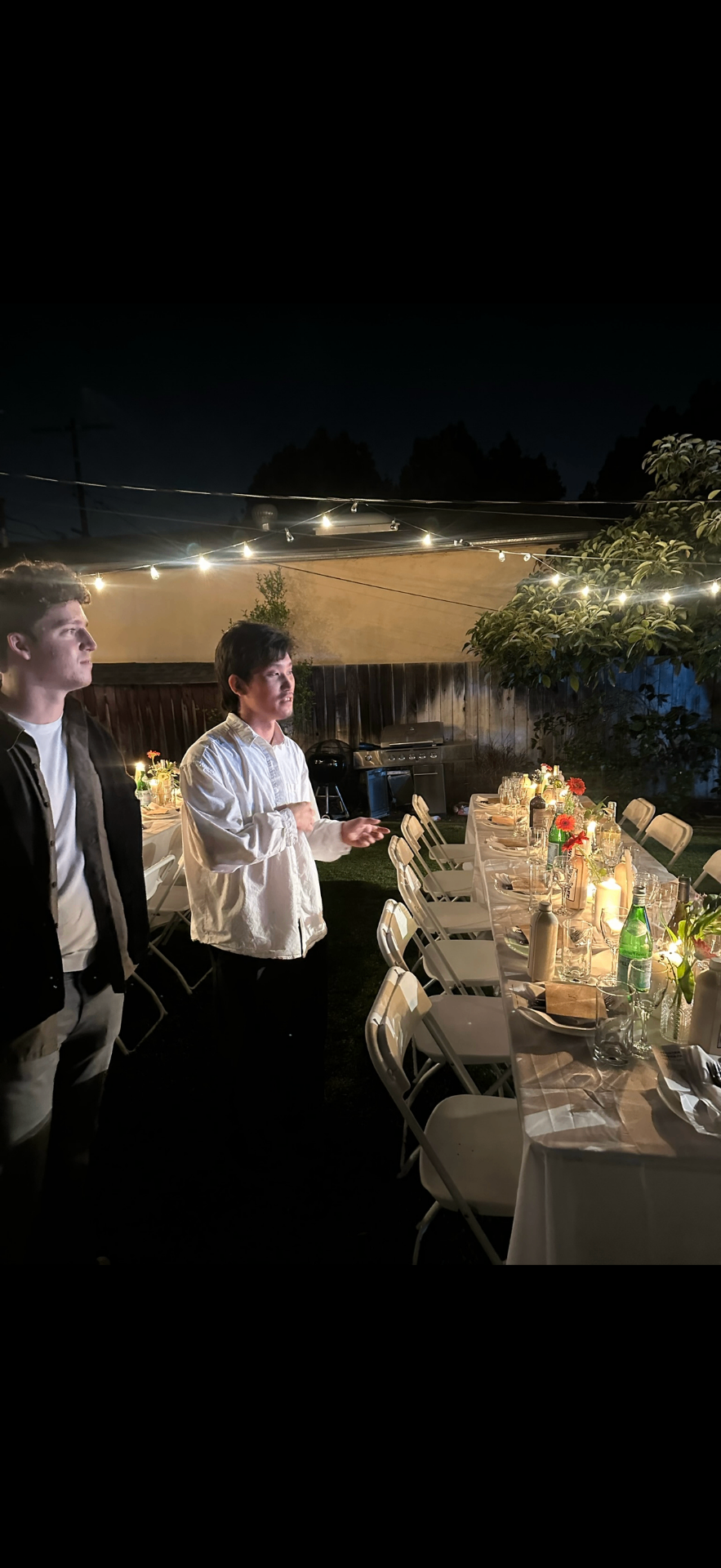 Guests speaking beside a beautifully set dinner table at night