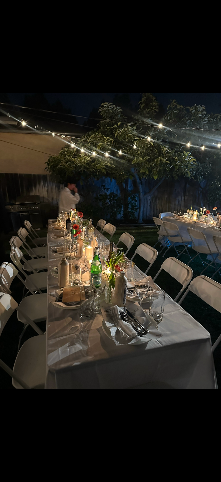 String-lit outdoor event setup with tables and floral details