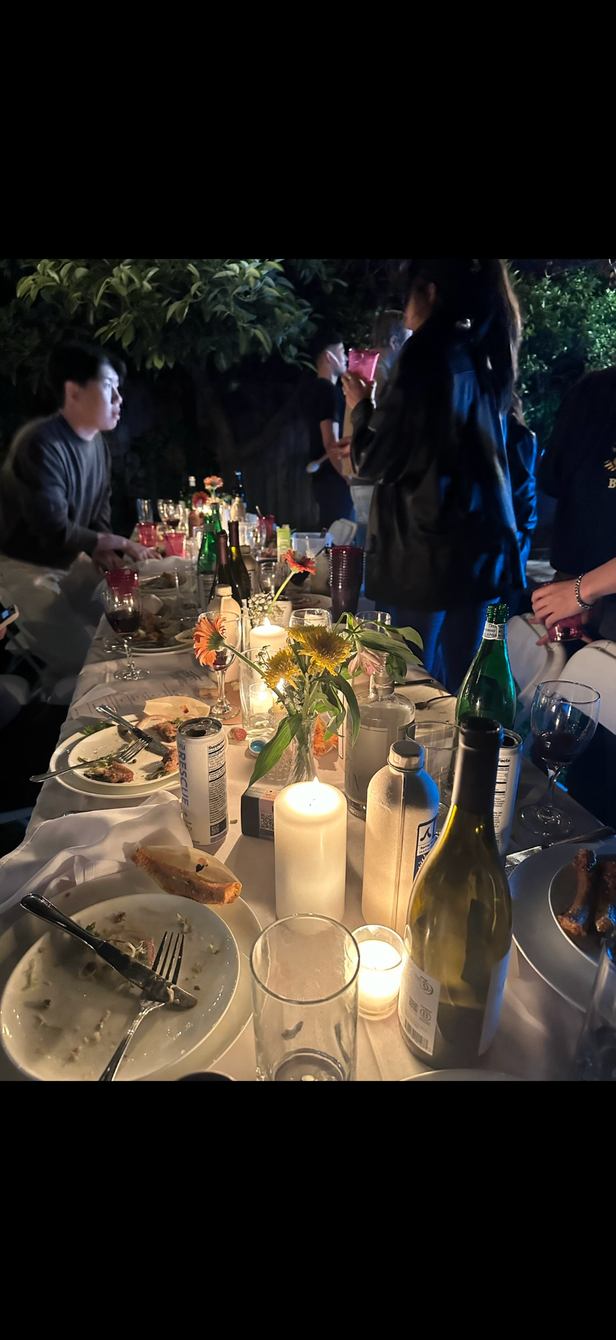 Close-up of a lively dinner table with candles, flowers, and drinks